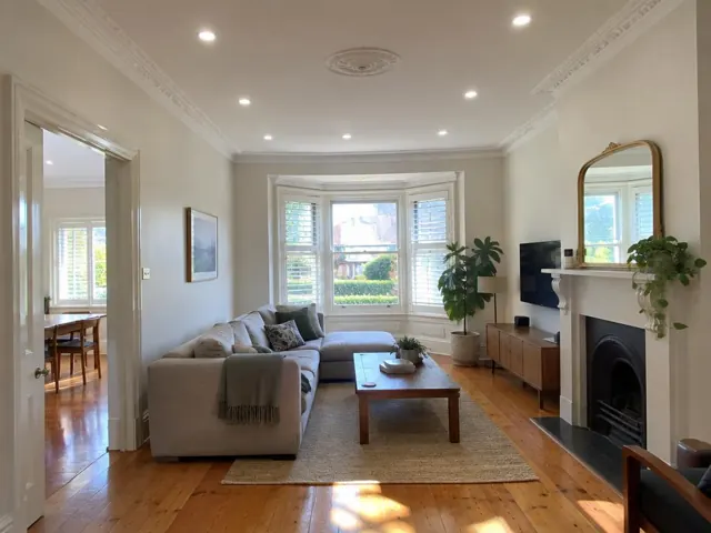 Living room with flush LED downlights, bay window, fireplace and timber floor in Bronte
